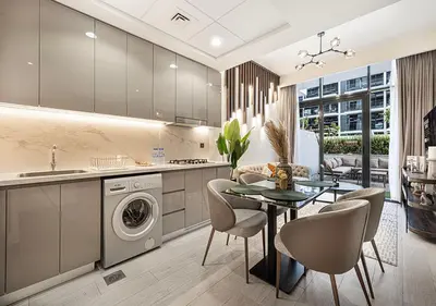 a kitchen with a washing machine and a table and chairs at 1BR Gem with Pool 15 Mins to Downtown Dubai in Dubai