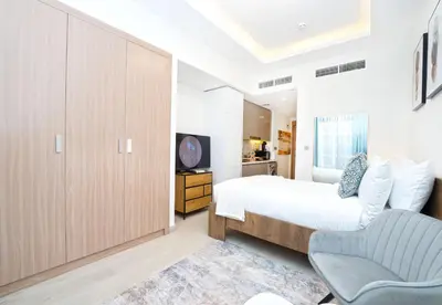 a bedroom with a bed and a chair and a television at EasyGo - Azizi Riviera 9 Bright Studio in Dubai