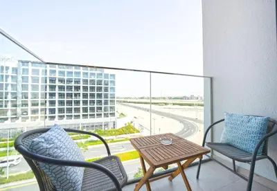 a balcony with two chairs and a table and a large window at EasyGo - Azizi Riviera 9 Bright Studio in Dubai