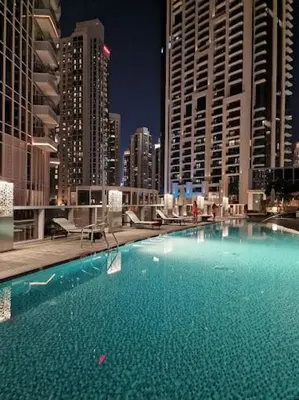 a large swimming pool in a city with tall buildings at Magnificent 3BR with Incredible Burj & Fountain View in Dubai