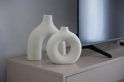 two white vases sitting on a table next to a television at Fresh & Quiet 1BR at Midtown Noor 4 Tower in Dubai
