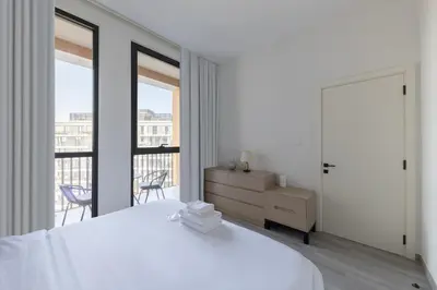a white bedroom with a bed and a balcony at Fresh & Quiet 1BR at Midtown Noor 4 Tower in Dubai