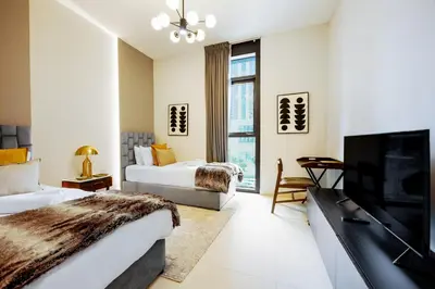 a bedroom with two beds and a flat screen tv at Stayis l 2BR Iconic Burj Khalifa View Partial in Dubai