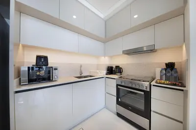 a white kitchen with a stove and a microwave at 2BR Emaar Beachfront with Full Sea & Skyline Views in Dubai