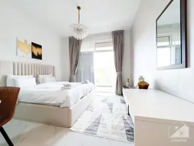 a white bedroom with a bed and a window at Stunning studio with Balcony in Arjan in Dubai