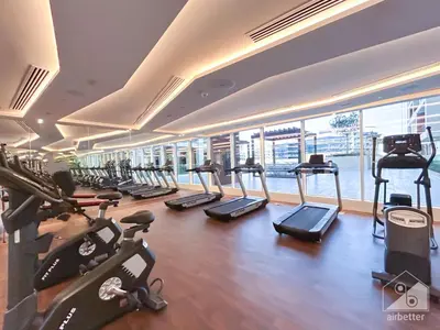 a gym with a row of treadmills and exercise bikes at Stunning studio with Balcony in Arjan in Dubai