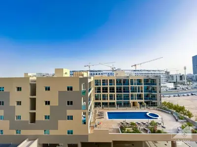 an apartment building with a swimming pool in front of it at Stunning studio with Balcony in Arjan in Dubai