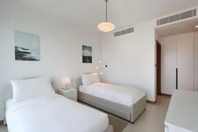 two beds in a room with white walls at Livbnb - Modern 3BR with Marina & Sunset View in Dubai