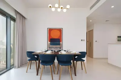 a dining room with a table and blue chairs at Maison Privee - Modern Chic Apt with Unobstructed Burj Khalifa Views in Dubai