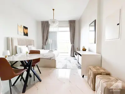 a white room with two beds and a table at Modern & Chic studio with Balcony Dubai in Dubai