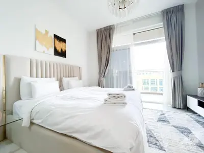a white bedroom with a large bed with a chandelier at Modern & Chic studio with Balcony Dubai in Dubai