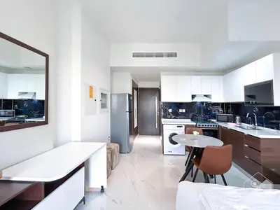 a kitchen with white cabinets and a table in it at Modern & Chic studio with Balcony Dubai in Dubai
