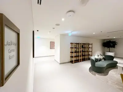 a living room with a green chair and a book shelf at HiGuests - Tranquil Luxury 1BR Apt in the Heart of the City in Dubai