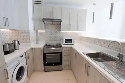 a white kitchen with a stove and a sink at Modern 1 bedroom at Palm Jumeirah in Dubai