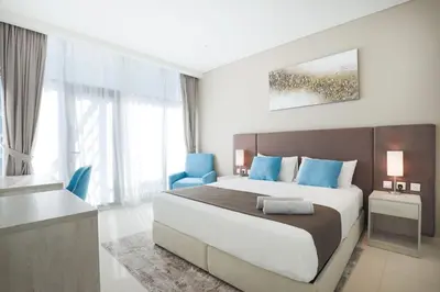 a bedroom with a large bed and a blue chair at Modern 1 bedroom at Palm Jumeirah in Dubai