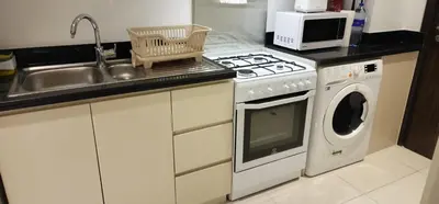 a kitchen with a stove and a washing machine at Carson Tower C - Damac Hills by Golden Casa in Dubai