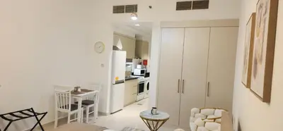 a kitchen with white cabinets and a table in a room at Carson Tower C - Damac Hills by Golden Casa in Dubai