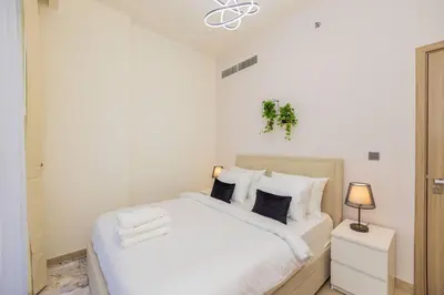 a white bedroom with a large white bed with pillows at Urban Charm: Luxe 1BR Haven Near Downtown Dubai in Dubai