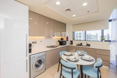 a kitchen with a table and chairs and a sink at Urban Charm: Luxe 1BR Haven Near Downtown Dubai in Dubai