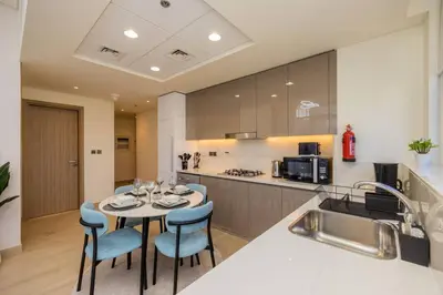 a kitchen with a table and some blue chairs at Urban Charm: Luxe 1BR Haven Near Downtown Dubai in Dubai