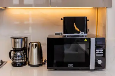a microwave sitting on top of a kitchen counter at Urban Charm: Luxe 1BR Haven Near Downtown Dubai in Dubai