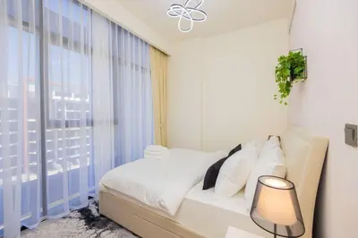 a white bedroom with a bed and a window at Urban Charm: Luxe 1BR Haven Near Downtown Dubai in Dubai