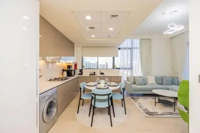 a kitchen and living room with a table and chairs at Urban Charm: Luxe 1BR Haven Near Downtown Dubai in Dubai