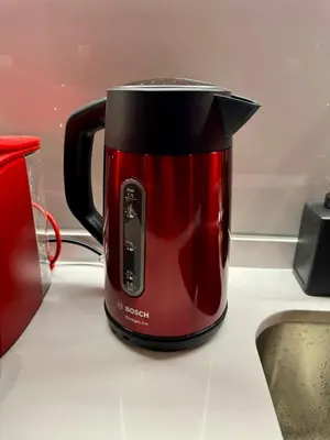 a red coffee pot sitting on a kitchen counter at Capsule Flora business bay view Burj Khalifa-pool table-game arcade-Projector-Playstation 5 in Dubai