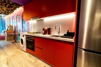 a kitchen with red cabinets and a sink and a dishwasher at Capsule Flora business bay view Burj Khalifa-pool table-game arcade-Projector-Playstation 5 in Dubai