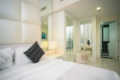 a white bedroom with a large white bed with pillows at LUX 1 bed flat with Burj Khalifa View - 3 minute walk to Dubai Mall - Best Location - Best Balcony View in Dubai