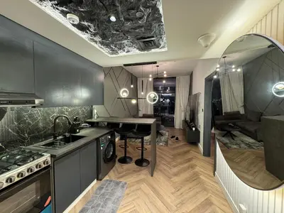 a kitchen with black cabinets and a sink and a table at Binghatti avenue in Dubai