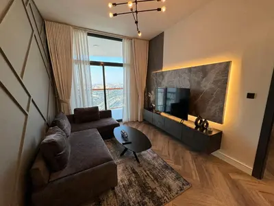 a living room with a couch and a television at Binghatti avenue in Dubai