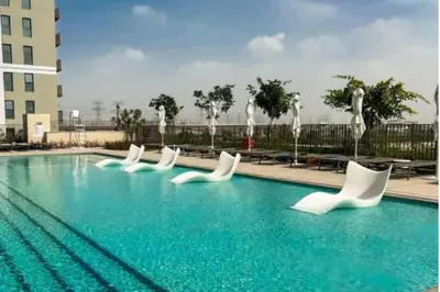 a swimming pool with white chairs in a building at Homesgetaway Luxury 2BR at Socio Dubai hills in Dubai