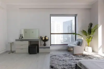 a white living room with a chair and a window at Stylish 3bdr apartment in Rimal 2 JBR in Dubai
