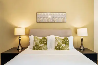 a bedroom with a white bed with two lamps at Spacious, Deluxe, 5BR plus maidroom on JBR walk Next to Beach ,Tram & Mall by La Buena Vida Holiday Homes in Dubai