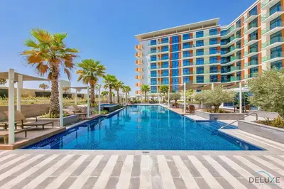 a swimming pool with palm trees and a building at Gorgeous Studio Apartment in DAMAC Celestia B Dubai South by Deluxe Holiday Homes in Dubai