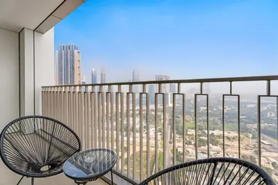 a balcony with two chairs and a view of a city at Silkhaus Elite 2BDR with View with Pool & Gym in Dubai
