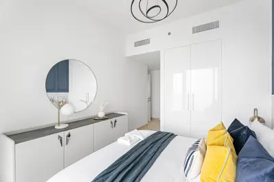 a white bedroom with a bed and a mirror at Silkhaus Elite 2BDR with View with Pool & Gym in Dubai