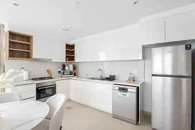 a kitchen with white cabinets and a stainless steel refrigerator at Silkhaus Elite 2BDR with View with Pool & Gym in Dubai