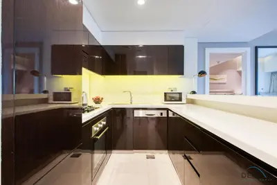 a kitchen with brown cabinets and a white counter top at Overlooking Canal Views, Fam-Friendly 2BR Unit, Damac Majestine Tower, Business Bay by Deluxe Holiday Homes in Dubai
