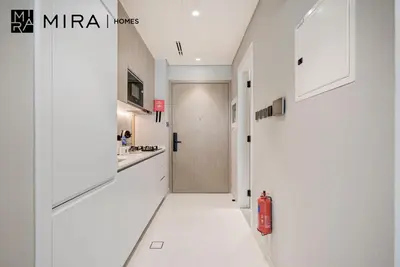 a white kitchen with a fire extinguisher on the floor at Mira Holiday Homes-Cozy studio close to metro in Dubai