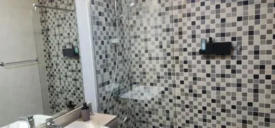 a bathroom with a sink and a shower with black and white tiles at Shaista Azizi Residence - Al Furjan by Golden Casa in Dubai