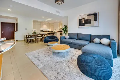 a living room with a blue couch and a table at Panoramic canal views from brand new 3BD apartment in Dubai