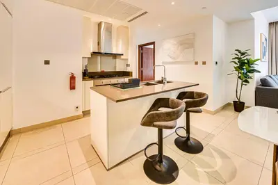 a kitchen with a counter and two bar stools at Panoramic canal views from brand new 3BD apartment in Dubai