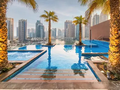 a swimming pool with palm trees and a city skyline at Panoramic canal views from brand new 3BD apartment in Dubai