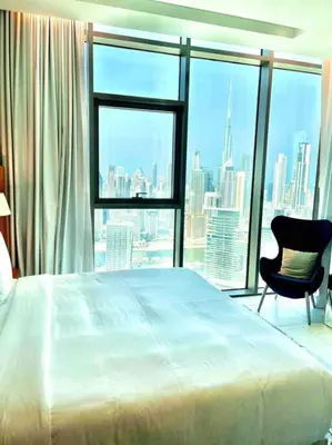 a bedroom with a bed and a chair and a large window at Best View Security System Burj Kalifa View in Dubai