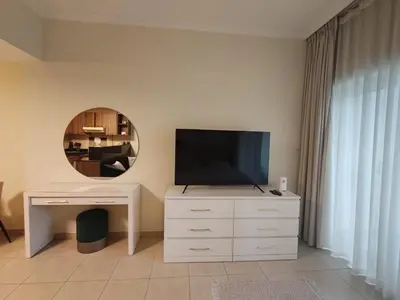 a living room with a television on a dresser with a mirror at Downtown Dubai Mall walk & Burj Khalifa DIFC 5 mins in Dubai