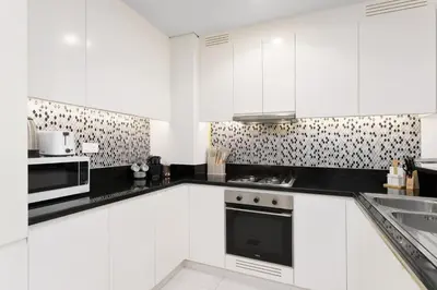 a white kitchen with white cabinets and appliances at Experience Opulent Living at Paramount Midtown in Dubai