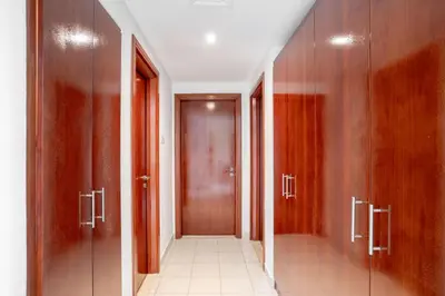 a hallway with wooden doors in a building at Lux BnB I Una Tower I Lakes View in Dubai