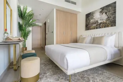 a bedroom with a large white bed with a painting on the wall at Frank Porter - Riviera 26 in Dubai